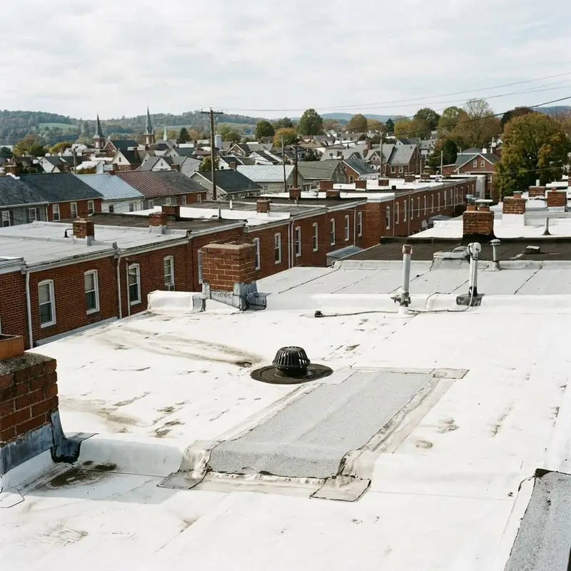 Low slope roof with a white membrane seam patch and drain